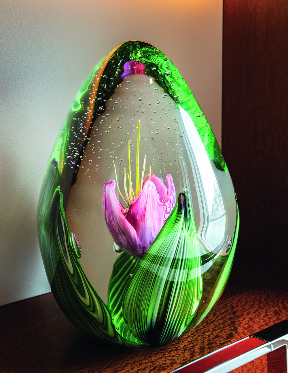 Glass orb with green leaves and a pink flower inside